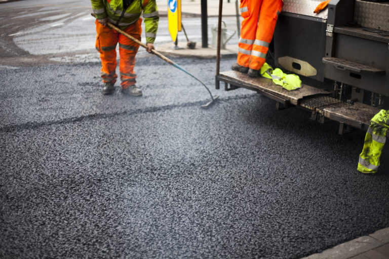 Workers in a parking lot new asphalt with workers, Road Roller Road Construction Machinery.