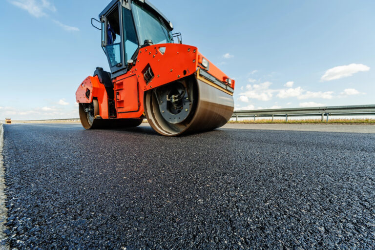 Asphalt compacting roller freshly poured asphalt in a parking lot