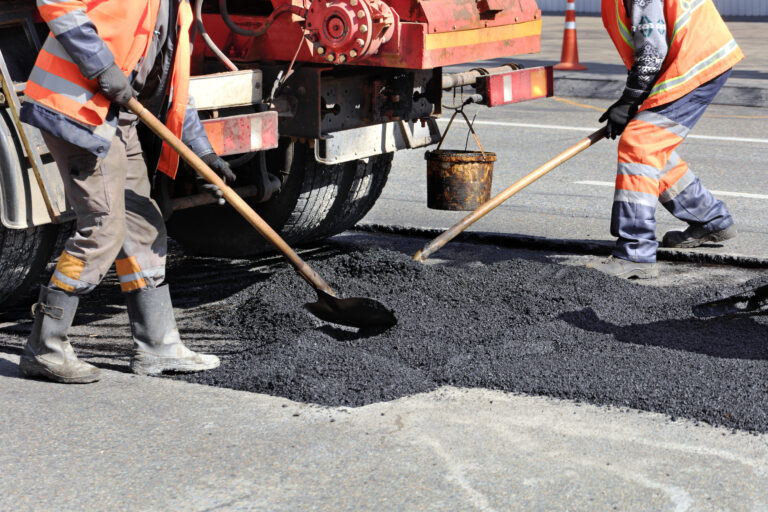 The road workers' working group renews a part of the road with fresh asphalt and levels it for repair in road construction.
