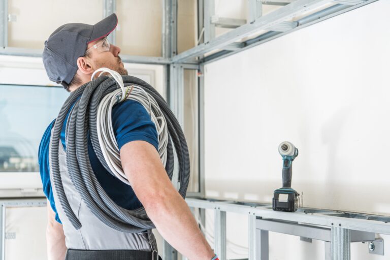 Electrician Ready For Work. Caucasian Electric Worker in His 30s with Pile of Cables on His Shoulder.