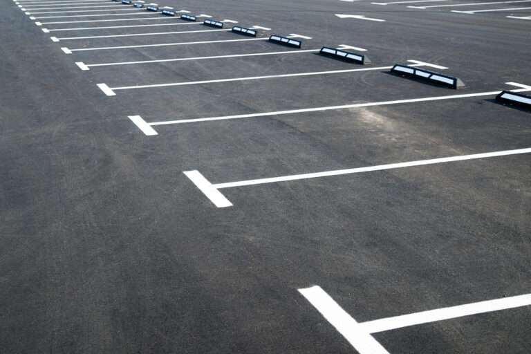 Markings on asphalt pavement indicating the parking lot in front of the store